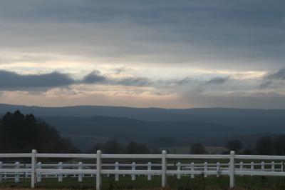 Paysage de collines pris depuis un balcon dont on voit la rambarde au premier plan.